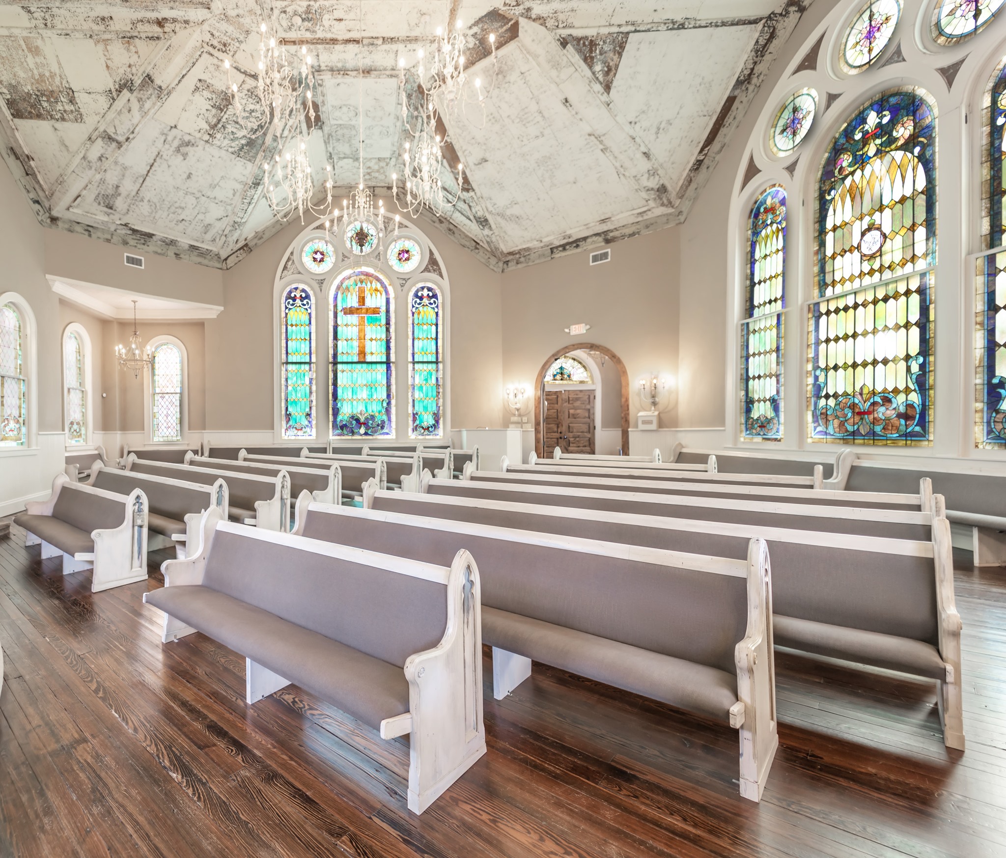church pews in historic church with large stained glass windows