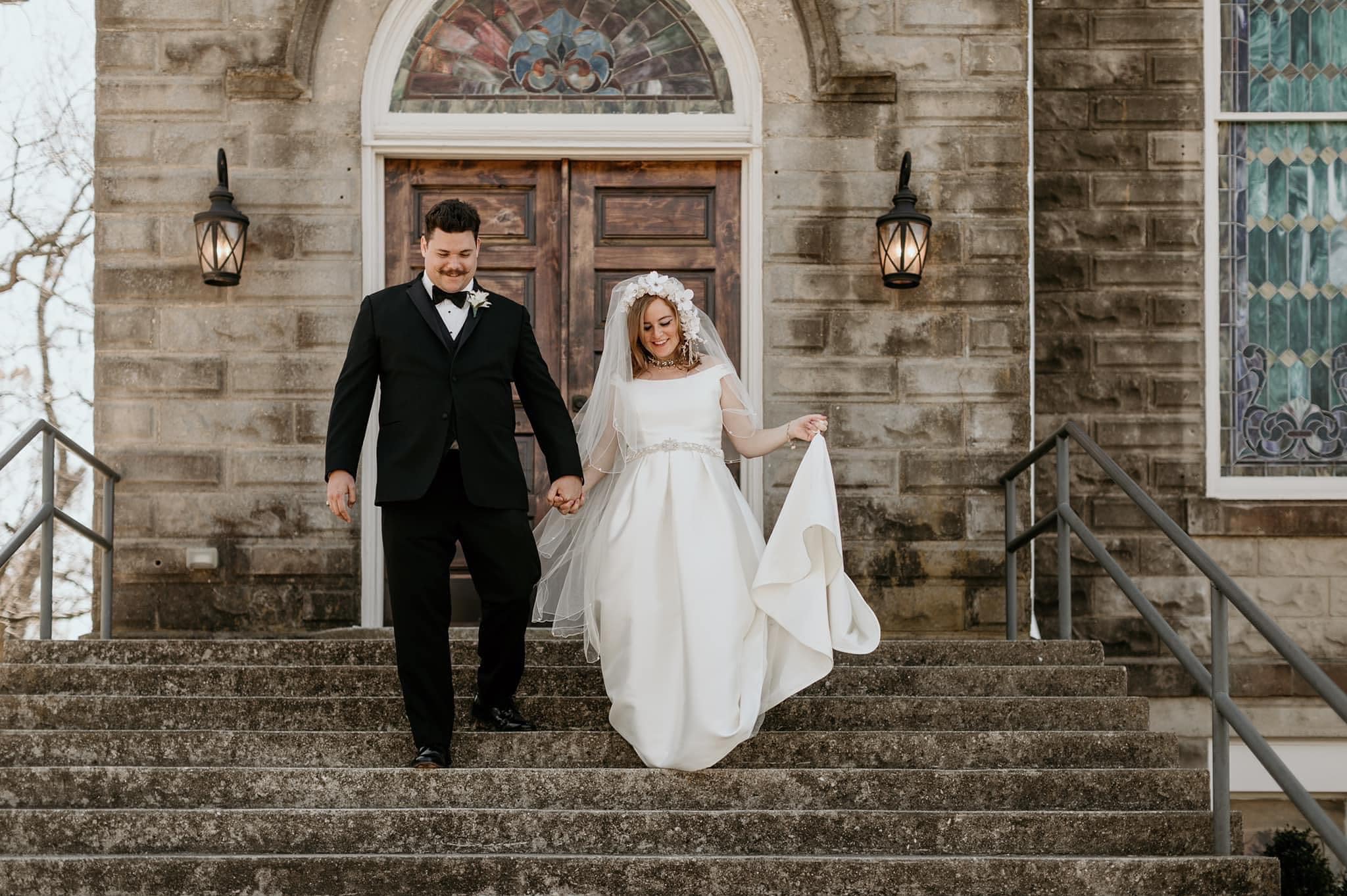 bride and groom walking down stone church steps