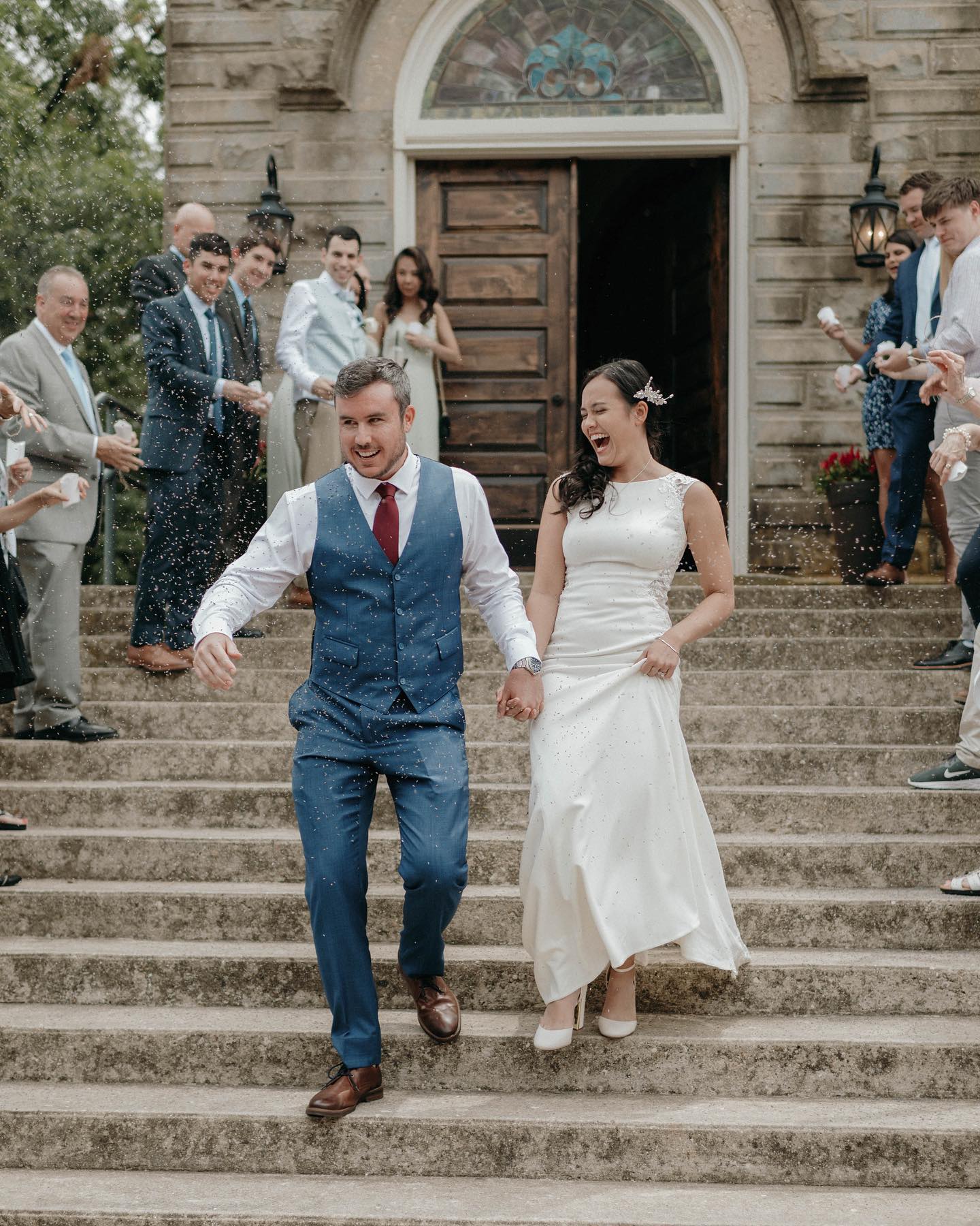 bride and groom walking down stone church steps