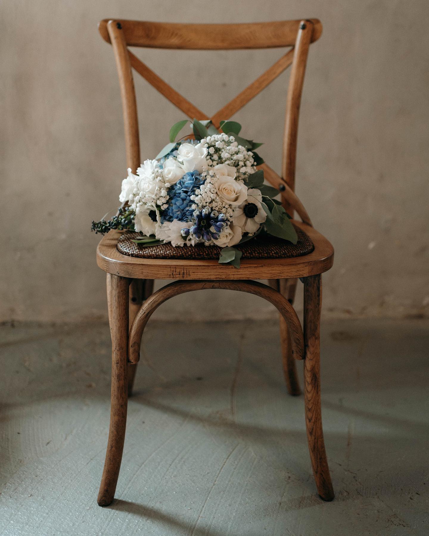 white and blue bridal bouquet in wooden chair